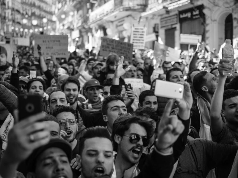 Crowded Algerian street protest captured with intensity and detail.